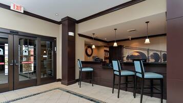 A hotel lobby with an exit sign, a reception desk, and three chairs.
