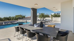 A modern outdoor dining area with a pool, lounge chairs, and a clear view of the surrounding landscape. - Nice home in Galizana (Galizana)