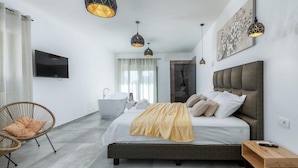 A modern bedroom with a large bed, a bathtub, and a TV mounted on the wall. - Nice home in Galizana (Galizana)