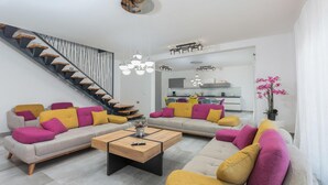 A modern living room with a staircase, a dining area, and a kitchen in the background. - Nice home in Galizana (Galizana)