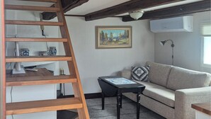 A living room with a wooden ladder, a sofa, a small table, a painting, and a lamp.