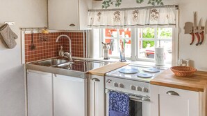 A compact kitchen with a sink, stove, and oven, featuring a window with a view of the outside.
