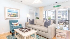 A living room with a beige sofa, a blue armchair, a coffee table, and a wicker side table.