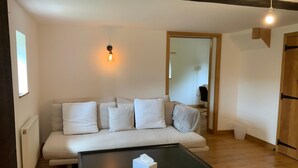 A cozy living room with a sofa, a small table, and a wooden floor.