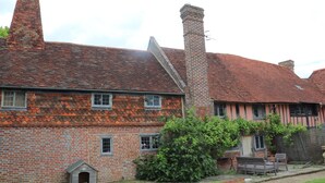 A traditional brick house with a tiled roof, a chimney, and a small doghouse.