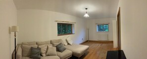 A living room with a sofa, two windows, a lamp, and a radiator. - Delightful 4BD Home Full of Flair Edenbridge Kent (Edenbridge)