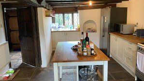 A kitchen with a wooden table, white cabinets, a built-in oven, and a window with a view of greenery.
