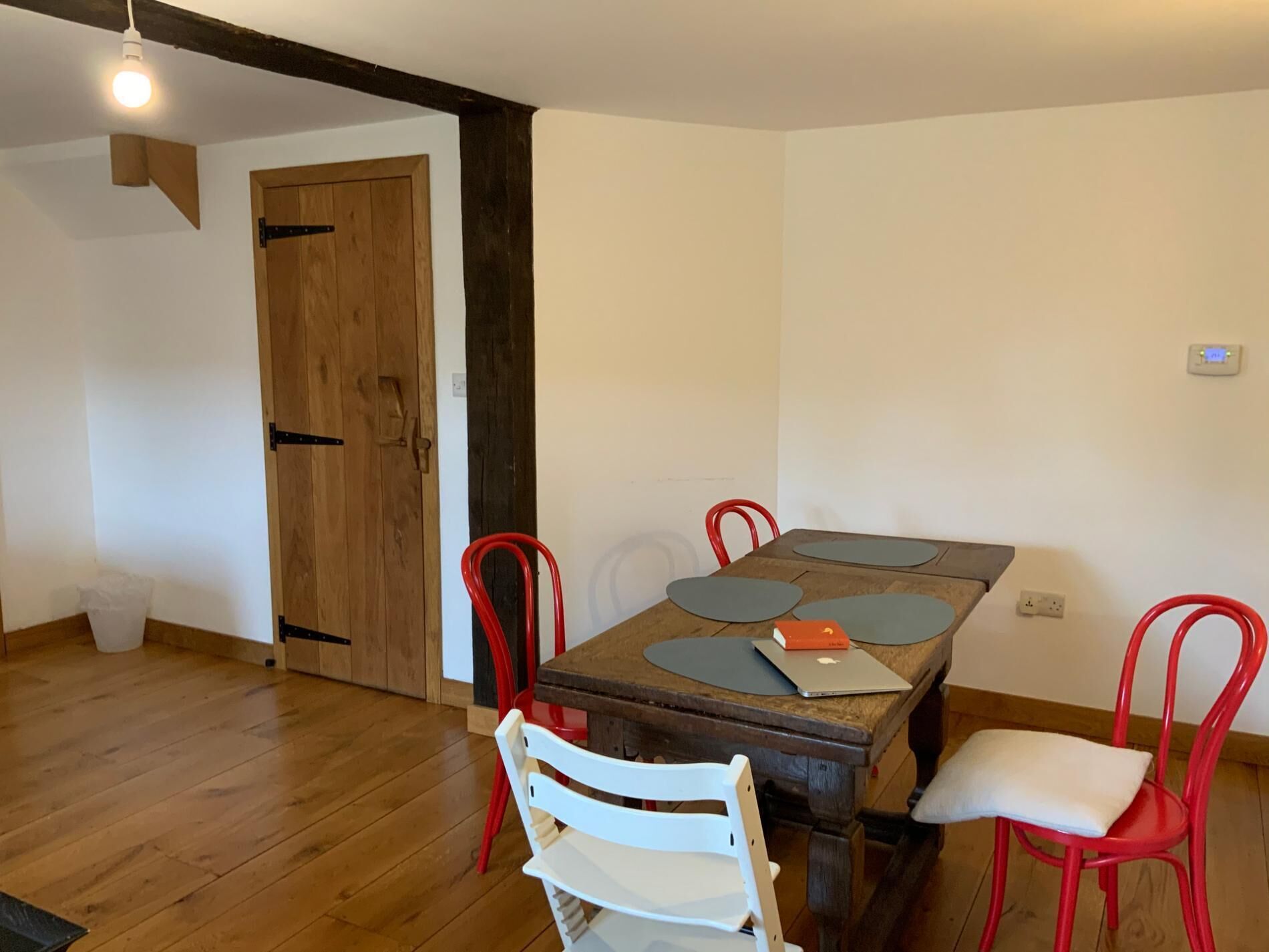 Een eetgedeelte met een houten tafel, vier stoelen en een laptop op tafel.