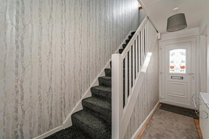 A staircase with a white railing, a door with a window, and a grey carpet.
