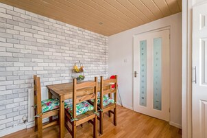 A dining area with a wooden table and chairs, a white brick wall, and a door with frosted glass panels.