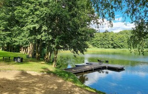 Un parque junto al lago con un muelle de madera, mesas de picnic y bancos.