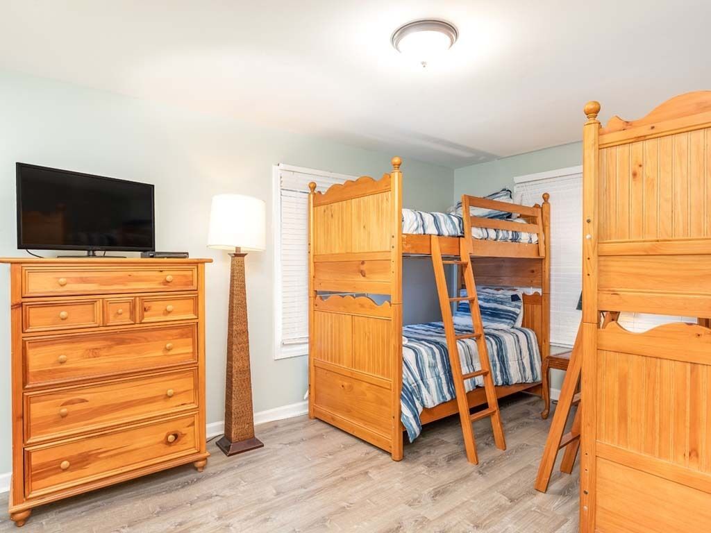 A bedroom with a bunk bed, a dresser, a television, and a lamp.