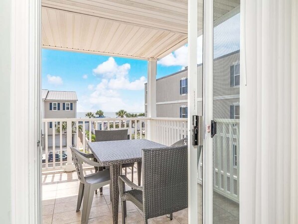 A balcony with a table and chairs, a white railing, and a view of neighboring buildings.