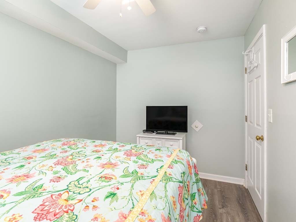 A bedroom with a floral bedspread, a flat-screen TV on a dresser, and a white door.