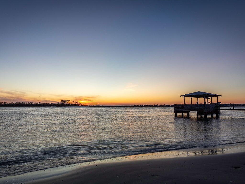 A beach with a wooden pier and a covered structure.