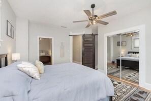 Relax in this stylish bedroom with a large bed, ceiling fan, and mirror.