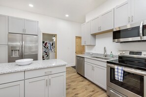 Modern kitchen with stainless steel appliances, white cabinetry, and a granite countertop.
