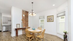Un coin repas avec une table ronde en bois et des chaises, un mur décoratif en briques et un luminaire suspendu.