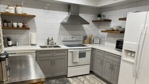 Una cocina moderna con armarios blancos, un lavamanos de acero inoxidable, horno empotrado y refrigerador.