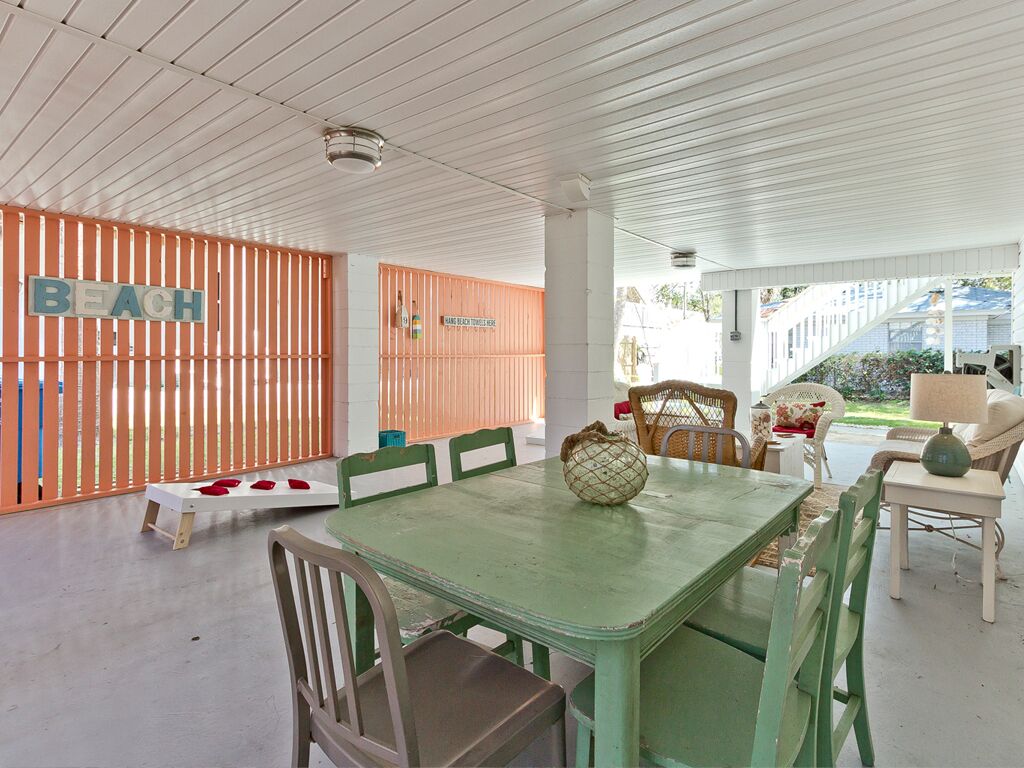 A beach-themed room with a wooden fence, a table with chairs, and a view of the beach.