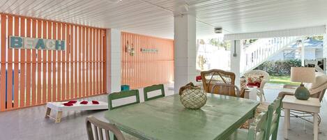 A beach-themed room with a wooden fence, a table with chairs, and a view of the beach.