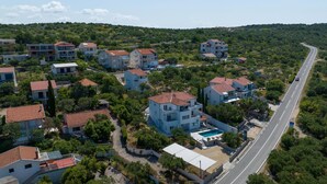 Vue aérienne d’un quartier résidentiel avec de nombreuses maisons à deux étages, une rue principale et une piscine.