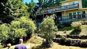 Ein zweistöckiges Gebäude mit einem Balkon, umgeben von Bäumen und einer Rasenfläche.