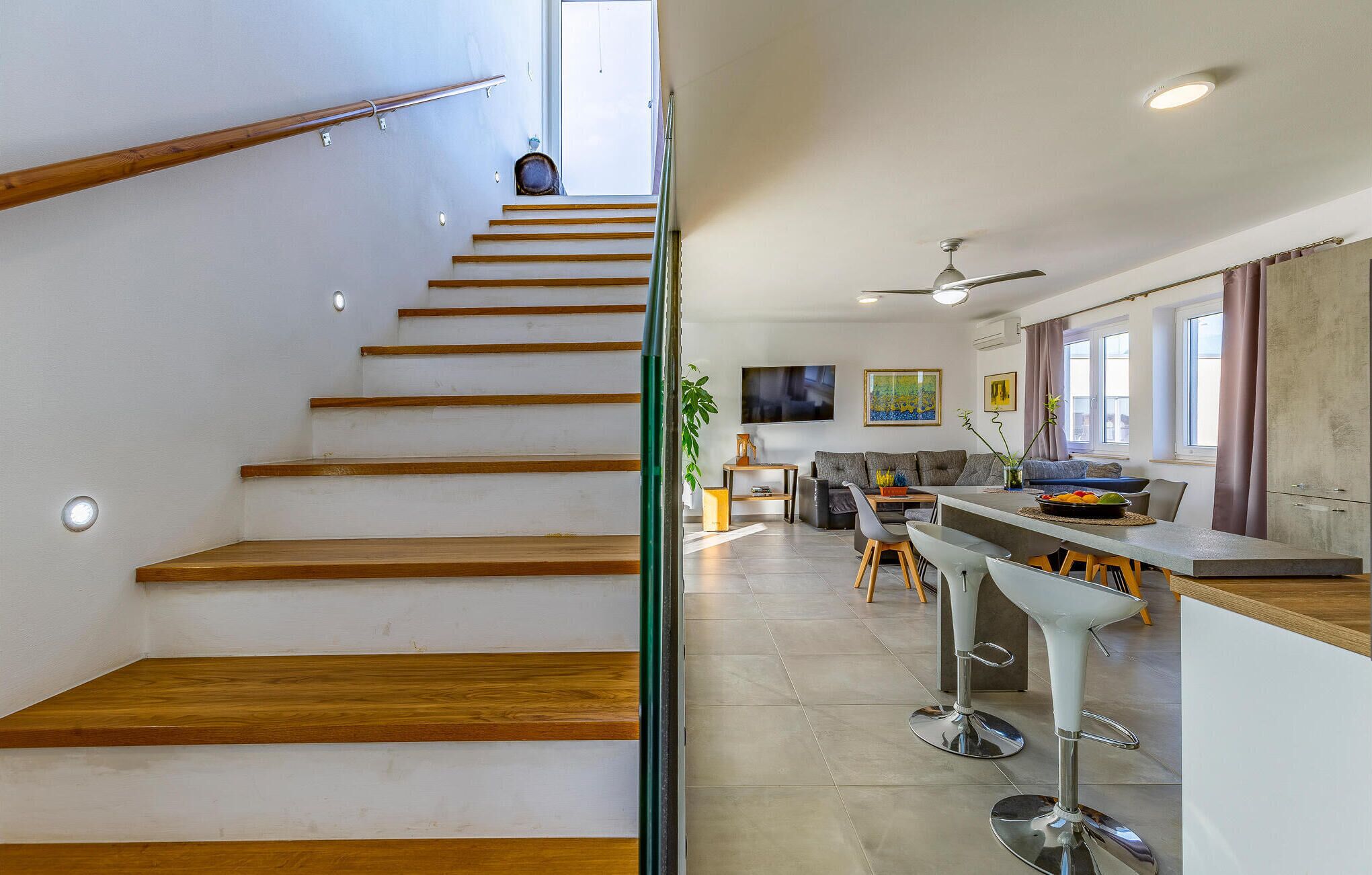 Una cocina moderna con comedor, una escalera de escalones de madera y un ventilador de techo.