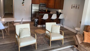 Una sala de estar moderna con comedor, una cocina con armarios de madera y una pequeña zona de bar.