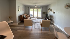 Un salón amplio con un sofá, dos sillones, una mesa de centro y un televisor.