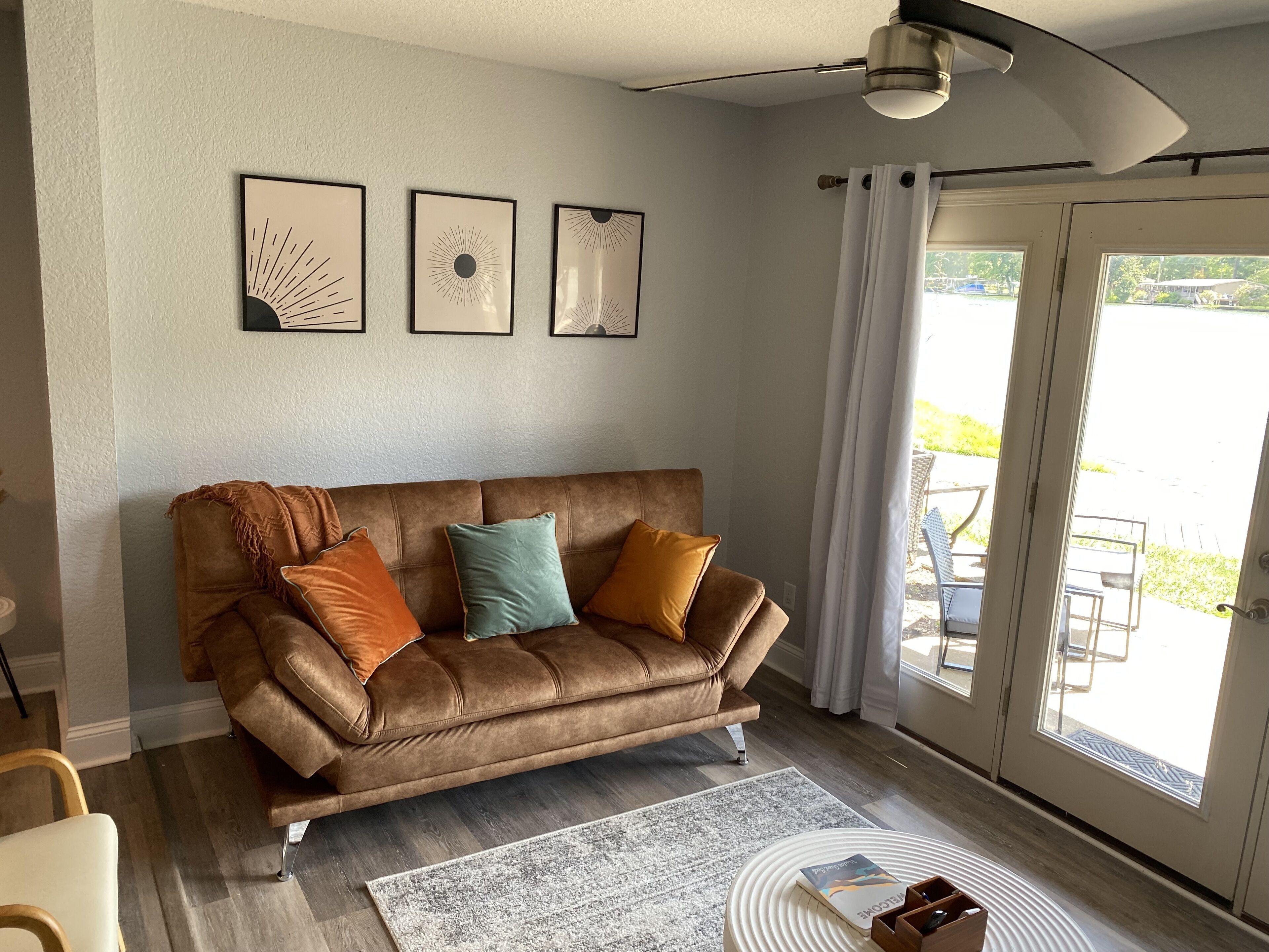 Ein braunes Ledersofa mit Kissen, ein gemustertes Teppich und gerahmte Wandbilder.