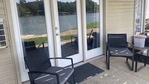 Un patio cubierto con dos sillas y una mesa, con vistas a un lago.