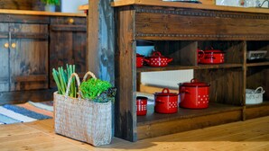 A kitchen with a wooden table and shelves holding red pots. - 4 bedroom cozy home in Banscica (Banscica)