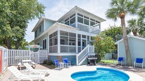 Ein zweistöckiges Haus mit Swimmingpool, Sitzgelegenheiten im Freien und einem umzäunten Garten.