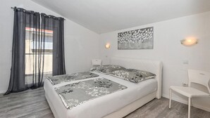 A bedroom with a bed, a chair, a painting, and a window with curtains. - 2 bedroom gorgeous apartment in Okrug Gornji (Okrug Gornji)