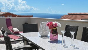 A balcony with a table, chairs, a vase with flowers, and a view of the sea and mountains. - 2 bedroom gorgeous apartment in Okrug Gornji (Okrug Gornji)