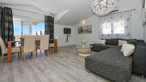 A modern living room with a grey sofa, a round coffee table, and a dining area with a table and chairs. - 2 bedroom gorgeous apartment in Okrug Gornji (Okrug Gornji)
