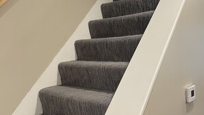 A staircase with carpeted steps leading up to a landing. - Dubuque Luxury Rentals Washington Street (Dubuque)
