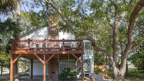 A wooden deck with a brick chimney, surrounded by trees. - Toes in the Sand by Tybee Vacation Rentals (Tybee Island)