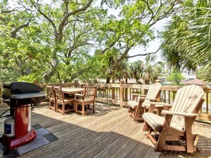 Enjoy al fresco dining on the deck surrounded by lush greenery and a barbecue grill.