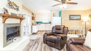 A living room with a fireplace, leather recliner, and a ceiling fan. - Toes in the Sand by Tybee Vacation Rentals (Tybee Island)