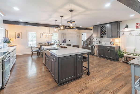 A spacious kitchen with a central island, dark cabinetry, and a wooden floor.