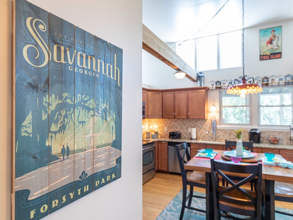A kitchen with wooden cabinets, a dining table with chairs, and a hanging light fixture.