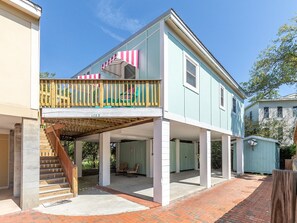 A two-story house with a covered porch, a staircase, and a small shed in the background. - Treetop Cottage by Tybee Vacation Rentals (Tybee Island)