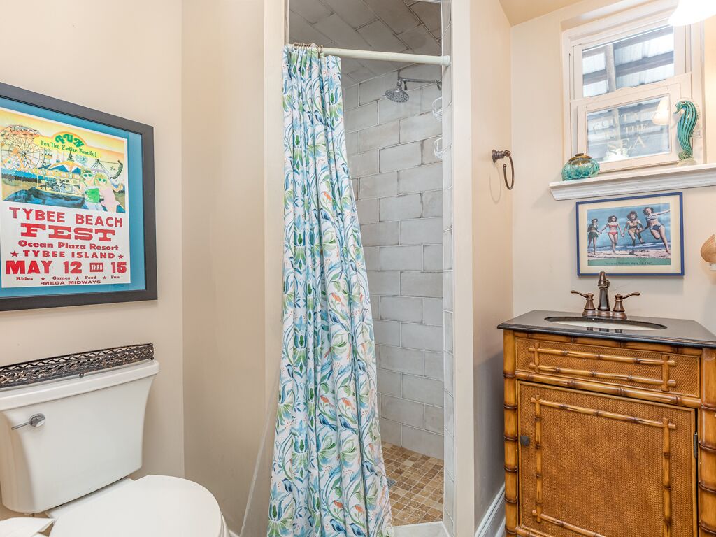 A bathroom with a shower curtain, a framed poster, a sink, and a cabinet.