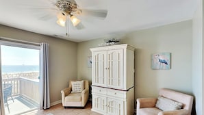 A room with a view of the beach, a white cabinet, two armchairs, and a coffee table. - Tybee Lights 112B by Tybee Vacation Rentals (Tybee Island)