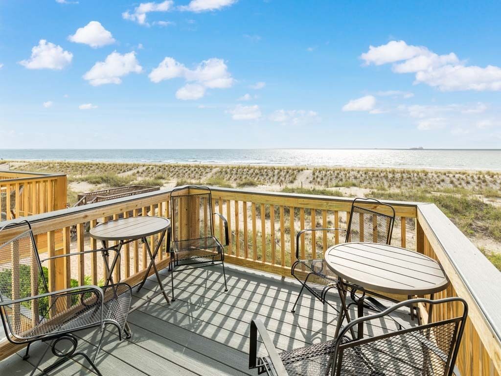 Une terrasse en bois avec des sièges extérieurs et une vue sur la plage.