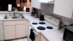 A modern kitchen with white cabinets, a stainless steel sink, a stove, and a microwave. - Charming Villa in Safety Harbor for the Family (Safety Harbor)