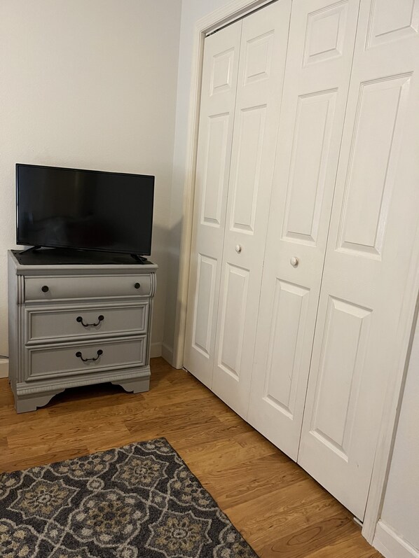 A room with a television on a dresser, a patterned rug, and white double doors. - Charming Villa in Safety Harbor for the Family (Safety Harbor)