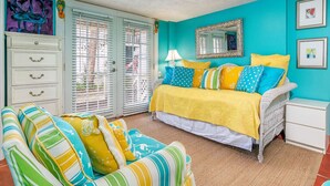 A bedroom with a bed, a chair, a nightstand, and a dresser. - Tybreeza A by Tybee Vacation Rentals (Tybee Island)